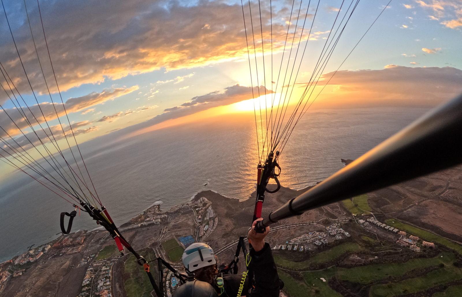 Legs dangling over Costa Adeje at golden hour, sunset over the Atlantic