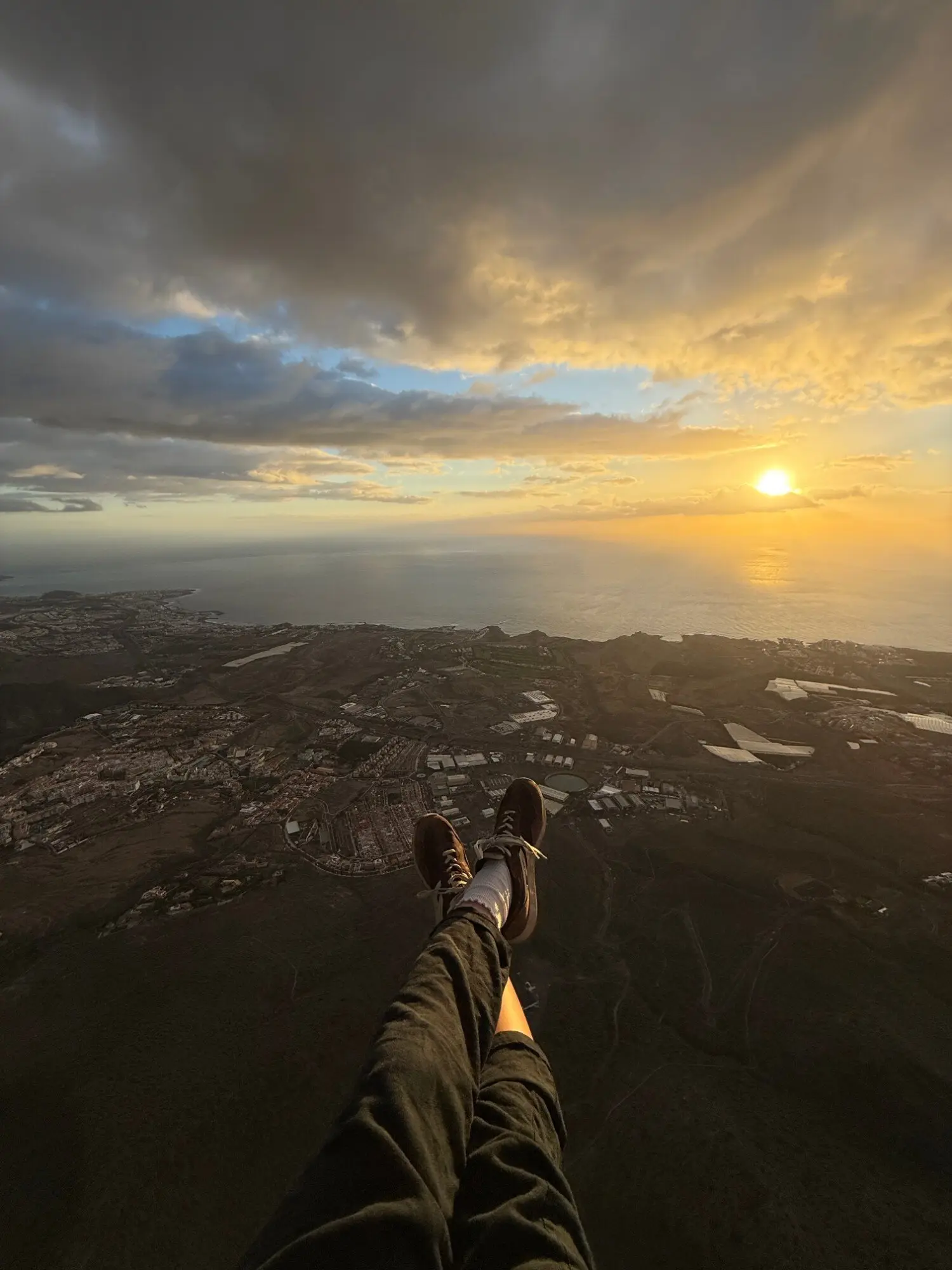 Legs dangling over Costa Adeje at golden hour, sunset over the Atlantic